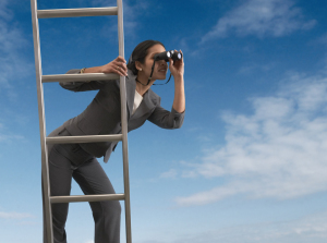 Businesswoman standing on a ladder looking through binoculars